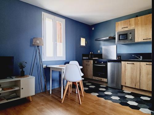 une cuisine avec des murs bleus et une table et des chaises dans l'établissement Appartement Cosy proche gare, à Narbonne