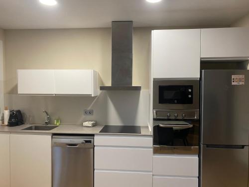 uma cozinha com armários brancos e um frigorífico de aço inoxidável em La Rotonda em Cardona