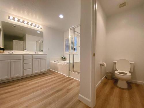 a white bathroom with a toilet and a sink at Golf course house with 2 Master Bedrooms in Fontana
