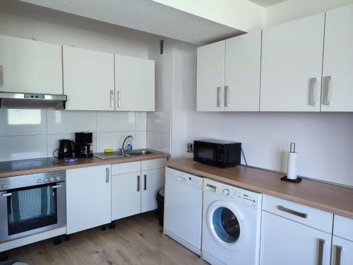 une cuisine avec des armoires blanches et une laveuse et une sécheuse dans l'établissement Moderne Ferienwohnung Messe Monteurwohnung Business Appartement Ratingen 4-5 P, Flughafen Düsseldorf, à Ratingen