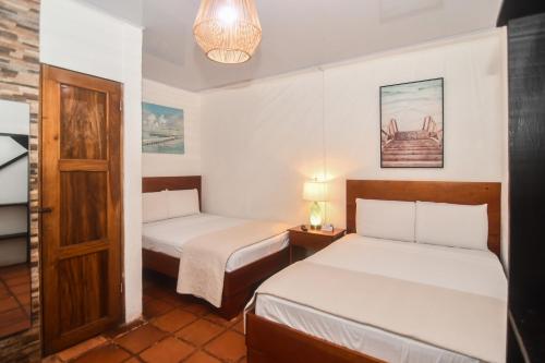 a small room with two beds and a door at Hotel Aldea Pura Vida in Puntarenas