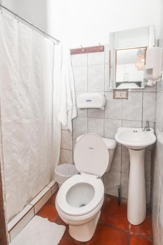 a white bathroom with a toilet and a sink at Hotel Aldea Pura Vida in Puntarenas
