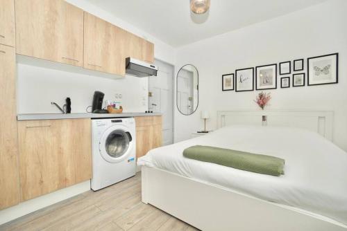 - une chambre blanche avec un lit et un lave-linge dans l'établissement Le temple du calme, à Metz