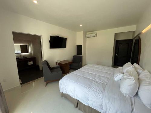 a bedroom with a large white bed and a desk at El Laurel Hotel Boutique in Xochitepec