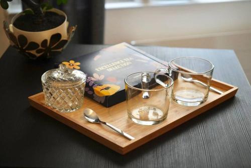 - un plateau en bois avec des verres et un livre sur une table dans l'établissement Le temple du calme, à Metz