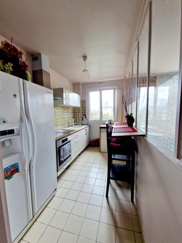 Il comprend une cuisine équipée d'un réfrigérateur blanc et d'une table. dans l'établissement location chambre chez l'habitant, à Épinay-sur-Seine