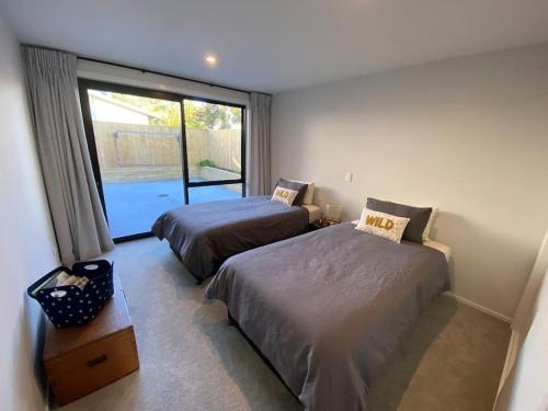 1 dormitorio con 2 camas y ventana grande en Luxury Escape in CBD - entire brand new home, en Tauranga