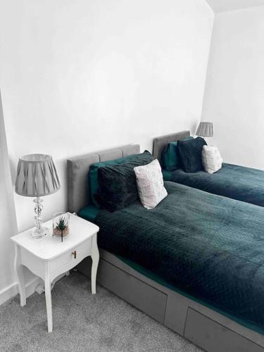 a bedroom with a bed and a table with a lamp at Spacious Modern Duplex Apartment in Rochdale
