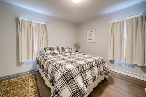 een slaapkamer met een bed met een geruite deken en 2 ramen bij Quaint Ripley Retreat - 5 Mi to Ripley Beach! in North East