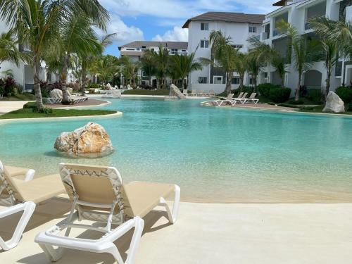 a resort swimming pool with chairs and a rock in the water at Komfortowy Apartament z 4 Basenami i Pięknym Ogrodem, Estrella Dominicus-Bayahibe in Bayahibe