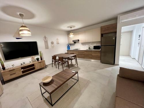 a living room with a table and a kitchen at Komfortowy Apartament z 4 Basenami i Pięknym Ogrodem, Estrella Dominicus-Bayahibe in Bayahibe