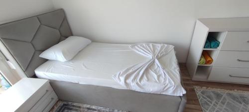 a small bedroom with a bed with white sheets at Sabi Apartment Golem Qerret in Golem