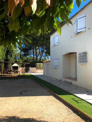 a white building with a driveway next to a yard at Maison Méditerranéenne in Lattes