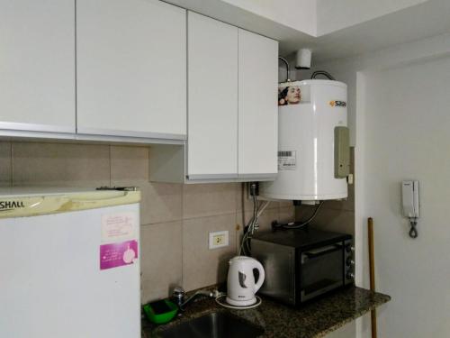 cocina con armarios blancos, fregadero y microondas en Abasto 2062 en Rosario