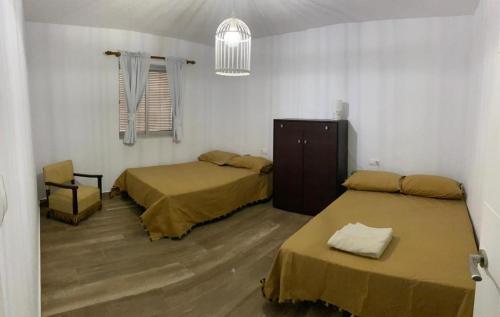 Habitación con 2 camas y una silla. en CASERIO LA SEVILLANA, en Baeza