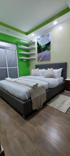 duże łóżko w pokoju z zieloną ścianą w obiekcie The Cot w mieście Kitengela 