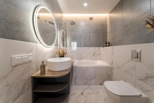 a bathroom with a sink and a tub and a toilet at 77 views apartments by INSHI in Lviv