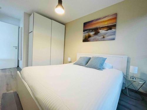 una camera da letto con un grande letto bianco con due cuscini blu di New One bedroom Flat- Terrace & Parking a Lussemburgo