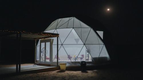 a glass dome building with a view of the ocean at Luxury Desert Camp Oman in Al Wāşil