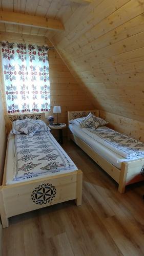 two beds in a wooden room with a window at Domki Białka & Apartamenty in Białka Tatrzanska