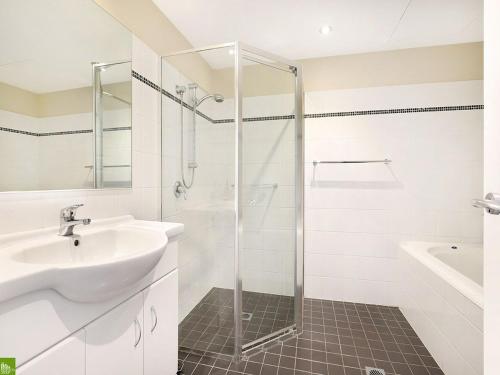 uma casa de banho branca com um lavatório e um chuveiro em It's Paradise Here, Guesthouse with Breakfast and 2 cats em Wollongong