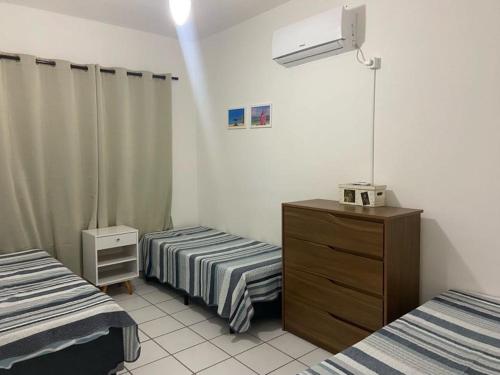グアルジャにあるApartamento aconchegante - Enseada - Guarujáのベッド2台とドレッサーが備わる客室です。