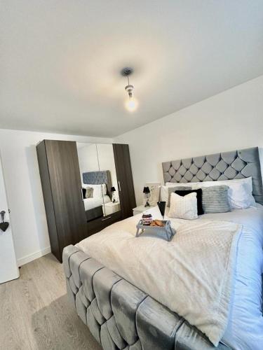 een slaapkamer met een groot bed met een grijs getuft hoofdeinde bij Modern and spacious flat in Longbridge