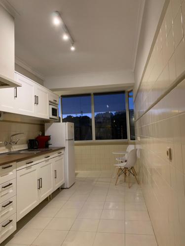 a kitchen with white appliances and a large window at Girassol apartamento in Alcabideche