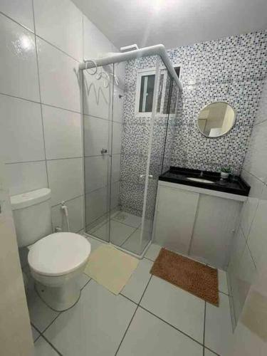 a white bathroom with a toilet and a shower at Apto com Ar com vista para praia de Morro Branco - Fortaleza in Beberibe