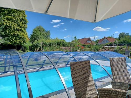 uma piscina com cadeiras e um telhado de vidro em Exklusive Dorfpension mit Pool und Sauna em Lage