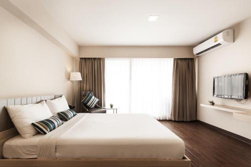 a bedroom with a large white bed and a window at Samran Place Hotel in Bangkok