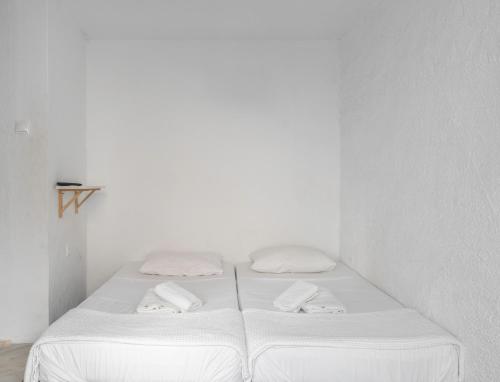 a white bedroom with two beds with towels on them at Detached house 1km from Acropolis Filopappou in Athens