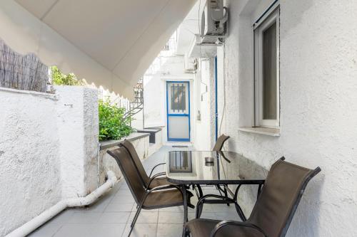 a table and chairs on a balcony with a blue door at Detached house 1km from Acropolis Filopappou in Athens