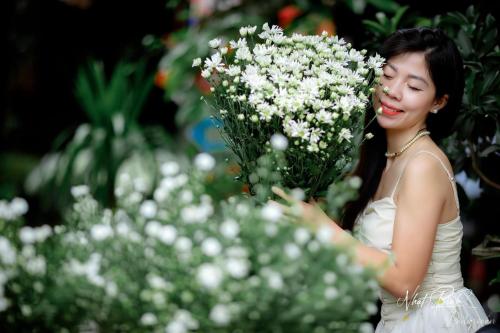 a woman holding a bunch of white flowers at Trầm Homestay in Thôn An Hòa