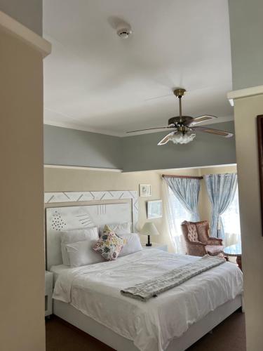a bedroom with a white bed with a ceiling fan at The KEDESAN Huis - Guest House in Johannesburg