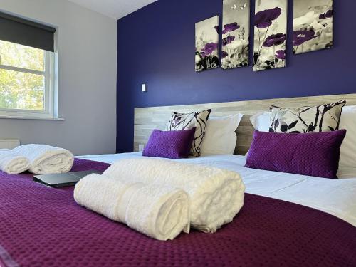 a bedroom with a large white bed with purple pillows at The Woolpack Inn in Kettering
