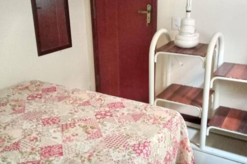 a bedroom with a bed and a table with a quilt at Apto no Centro de Conservatória in Conservatória