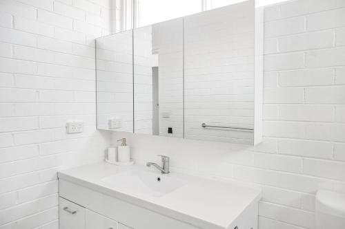 Baño blanco con lavabo y espejo en The Blue Whale - Sea View Apartment, en Eden