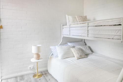 a white bedroom with a bed with white sheets and pillows at The Blue Whale - Sea View Apartment in Eden