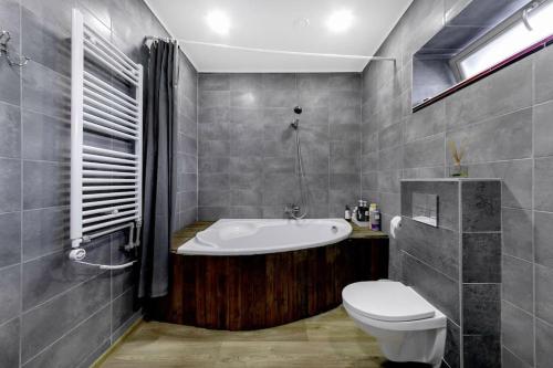 a bathroom with a bath tub and a toilet at Metal-House in Vievis