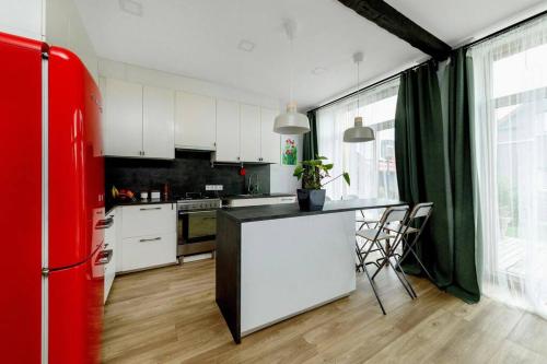 a kitchen with white cabinets and a red refrigerator at Metal-House in Vievis