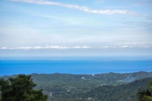 a view of the ocean from the top of a mountain at Taorayiná nature lodge- immersed in the forest in El Zaino
