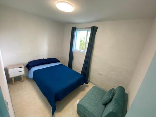 ein kleines Schlafzimmer mit einem blauen Bett und einem Sofa in der Unterkunft Casa Aurora Tibasosa Boyaca in Tibasosa