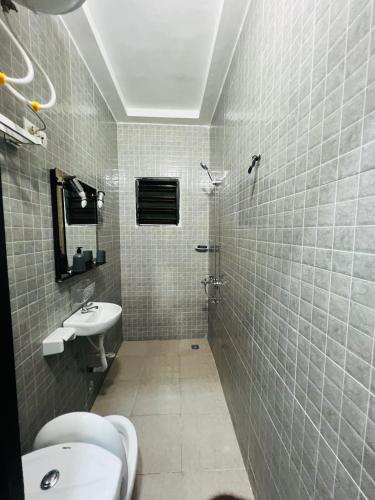a tiled bathroom with a sink and a toilet at Magnifique appartement meublé 2 chambres in Lomé