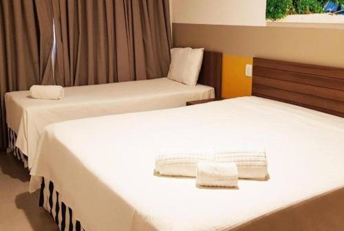 two beds with white sheets in a room at Enjoy Solar das Águas Olímpia in Olímpia