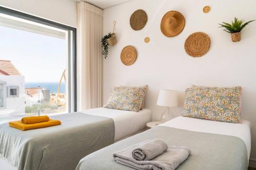 two beds in a room with a window at Beach, Ocean view & Bright House Ericeira in Ericeira