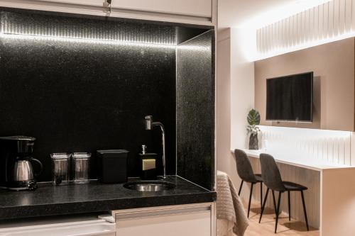 a kitchen with a counter with a sink and chairs at Suíte América na Pelinca in Campos dos Goytacazes