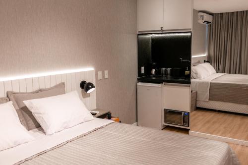 カンポス・ドス・ゴイタカゼスにあるSuíte América na Pelincaのベッドとキッチン付きの小さなホテルルームです。