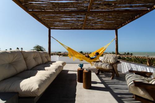 a porch with a couch and a hammock on the beach at Villa Aura, piscina privativa e rooftop com vista excepcional pro mar, 150m do mar e do Rancho do Kite, Praia do Prea in Prea