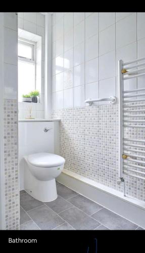 y baño blanco con aseo y ducha. en Spacious 3 bedroom house in nottingham, en Nottingham